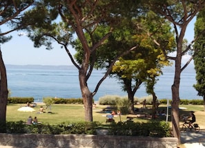 A park with trees, grass, and a body of water in the background. - Residence and Quiet Residence With Pool, Near the Lake (Lazise)