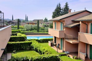 A residential building with a pool, green hedges, and a balcony. - Residence and Quiet Residence With Pool, Near the Lake (Lazise)