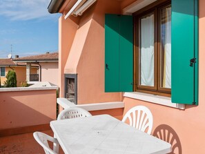 A small outdoor patio with a white table and chairs, a green window shutter, and a white curtain. - Residence and Quiet Residence With Pool, Near the Lake (Lazise)