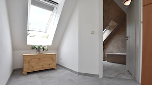 A modern interior with a wooden dresser, a skylight, and a view of a bathroom with a bathtub and shower. - Holiday Home in Damshagen With Terrace (Damshagen)