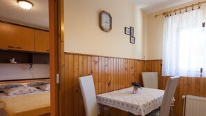 A small room with a bed, a table with chairs, a clock on the wall, and a window with curtains. - Cozy Apartment in Malinska near Sea (Malinska-Dubasnica)