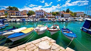 A marina with various boats docked, a stone wall in the foreground, and buildings in the background. - Cozy Apartment in Malinska near Sea (Malinska-Dubasnica)