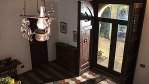 A room with a hexagonal patterned floor, a hanging light fixture, a wooden bench, and a door leading outside. - Charming Villa in Maida With Pool & Garden (San Pietro a Maida)