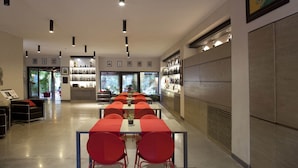 A modern restaurant with long tables and red chairs, a bar area with shelves of bottles, and a view of greenery outside. - Charming Villa in Maida With Pool & Garden (San Pietro a Maida)