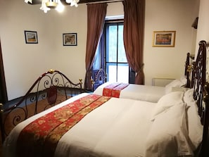 Een hotelkamer met twee bedden, een raam met gordijnen en een kroonluchter.