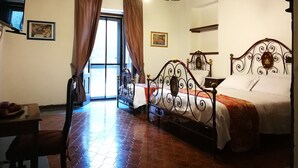 A bedroom with a double bed, a desk with a chair, a window with curtains, and a chandelier. - Charming Villa in Maida With Pool & Garden (San Pietro a Maida)