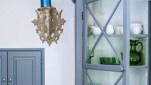 Une cuisine avec un meuble bleu, un meuble vitré et un appliques murales décoratif.