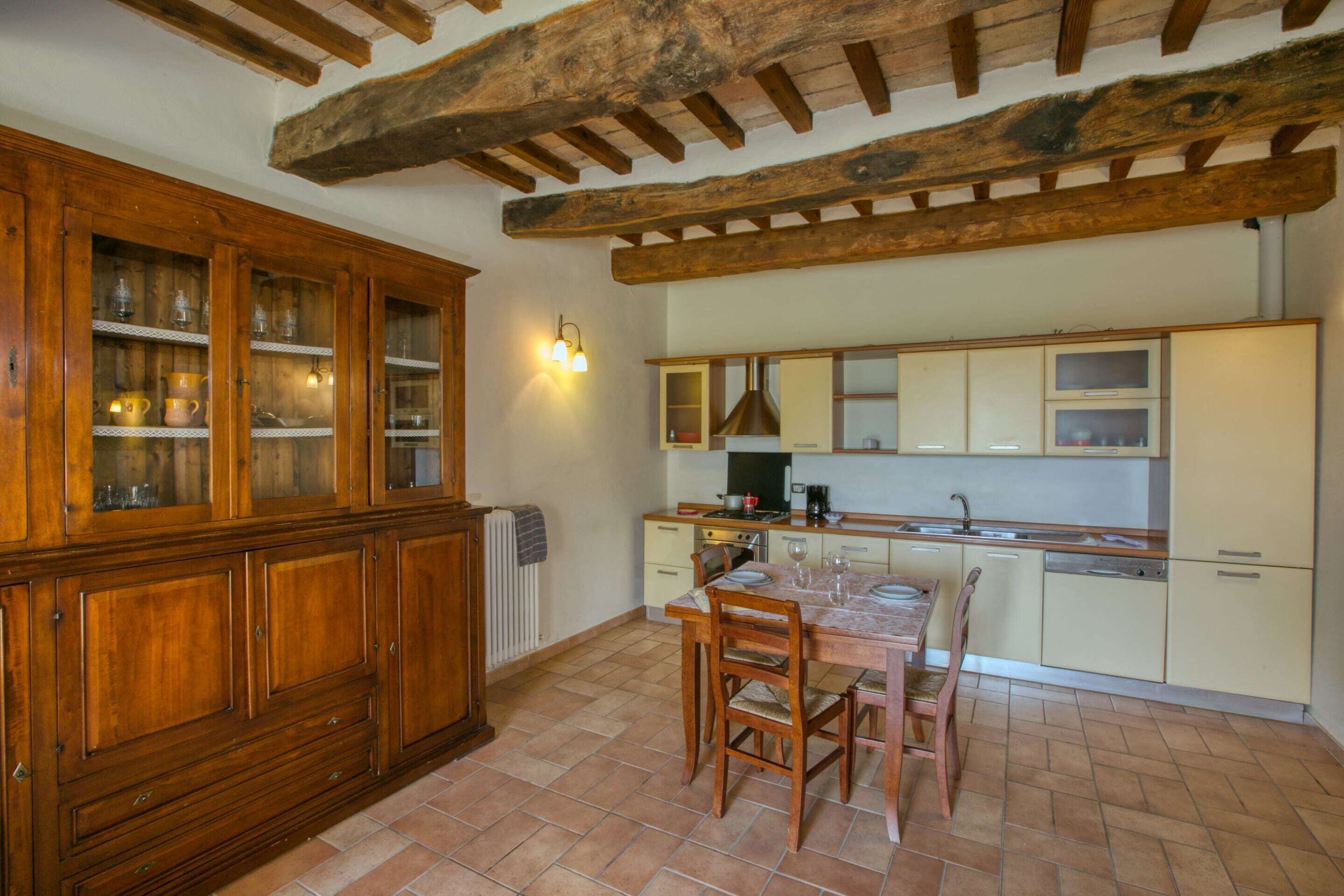 A kitchen with wooden cabinets, a dining table with chairs, and a tiled floor.