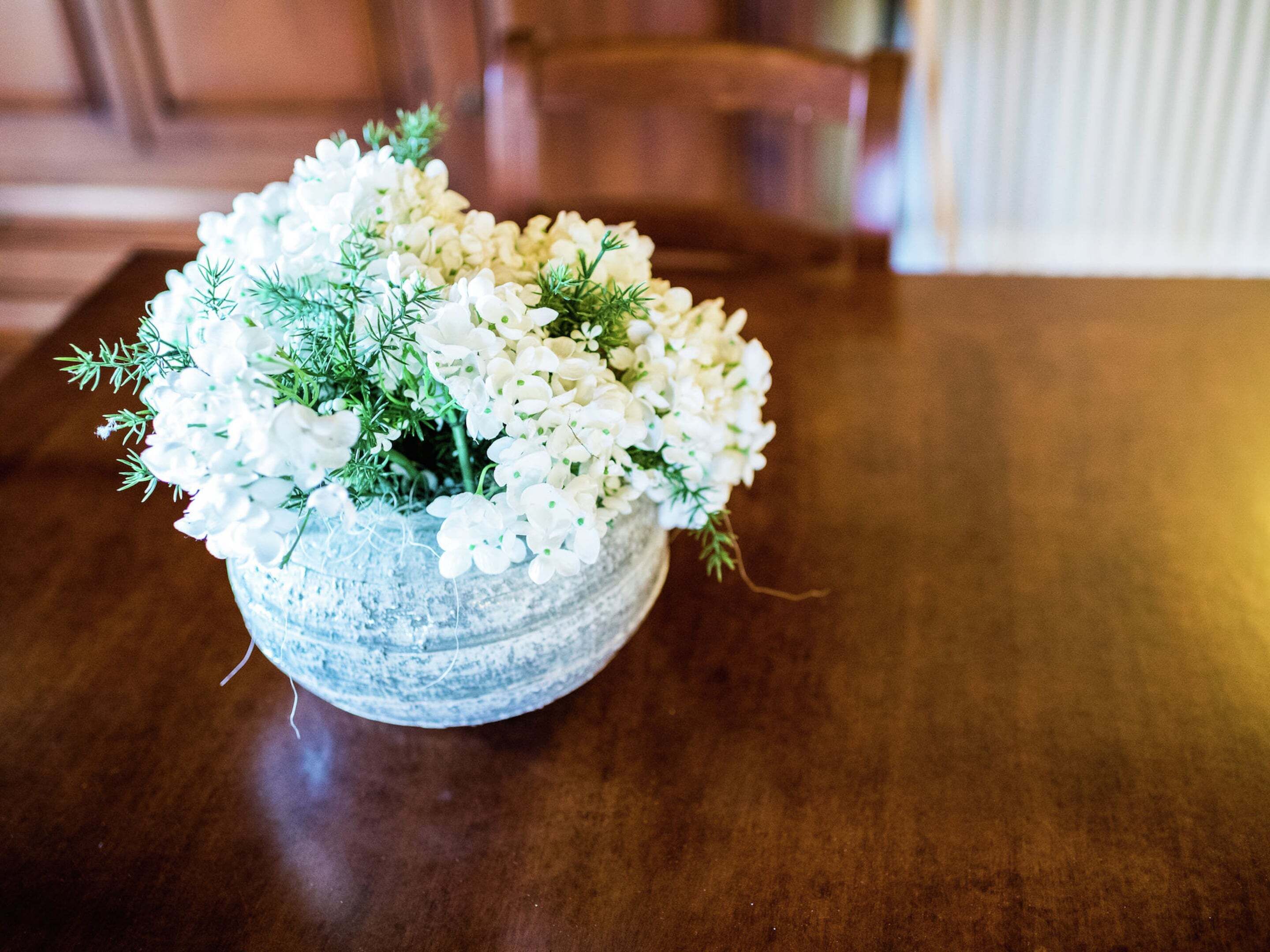 A floral arrangement in a textured bowl on a wooden table.