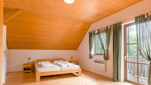 A bedroom with a wooden ceiling, a large window with curtains, a bed, and a nightstand. - Holiday Home With a Convenient Location in the Giant Mountains for Summer & Winter (Rudník)