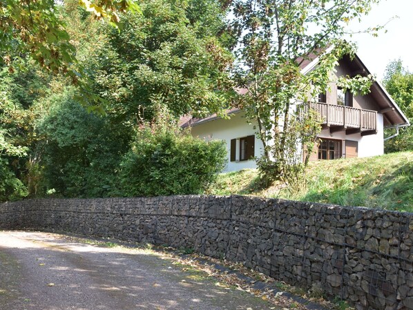 Un mur de pierre et une maison avec un balcon.