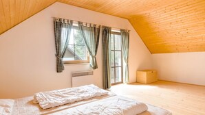 A bedroom with a sloped ceiling, a bed with white bedding, a window with curtains, and a radiator. - Holiday Home With a Convenient Location in the Giant Mountains for Summer & Winter (Rudník)
