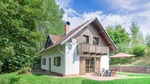 A two-story house with a balcony, a stone wall, and a patio with outdoor furniture. - Holiday Home With a Convenient Location in the Giant Mountains for Summer & Winter (Rudník)