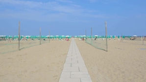 Un paseo marítimo bordeado de sillas y sombrillas de playa, que conduce al océano.