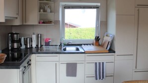 Cocina compacta con ventana, un reloj y varios electrodomésticos.