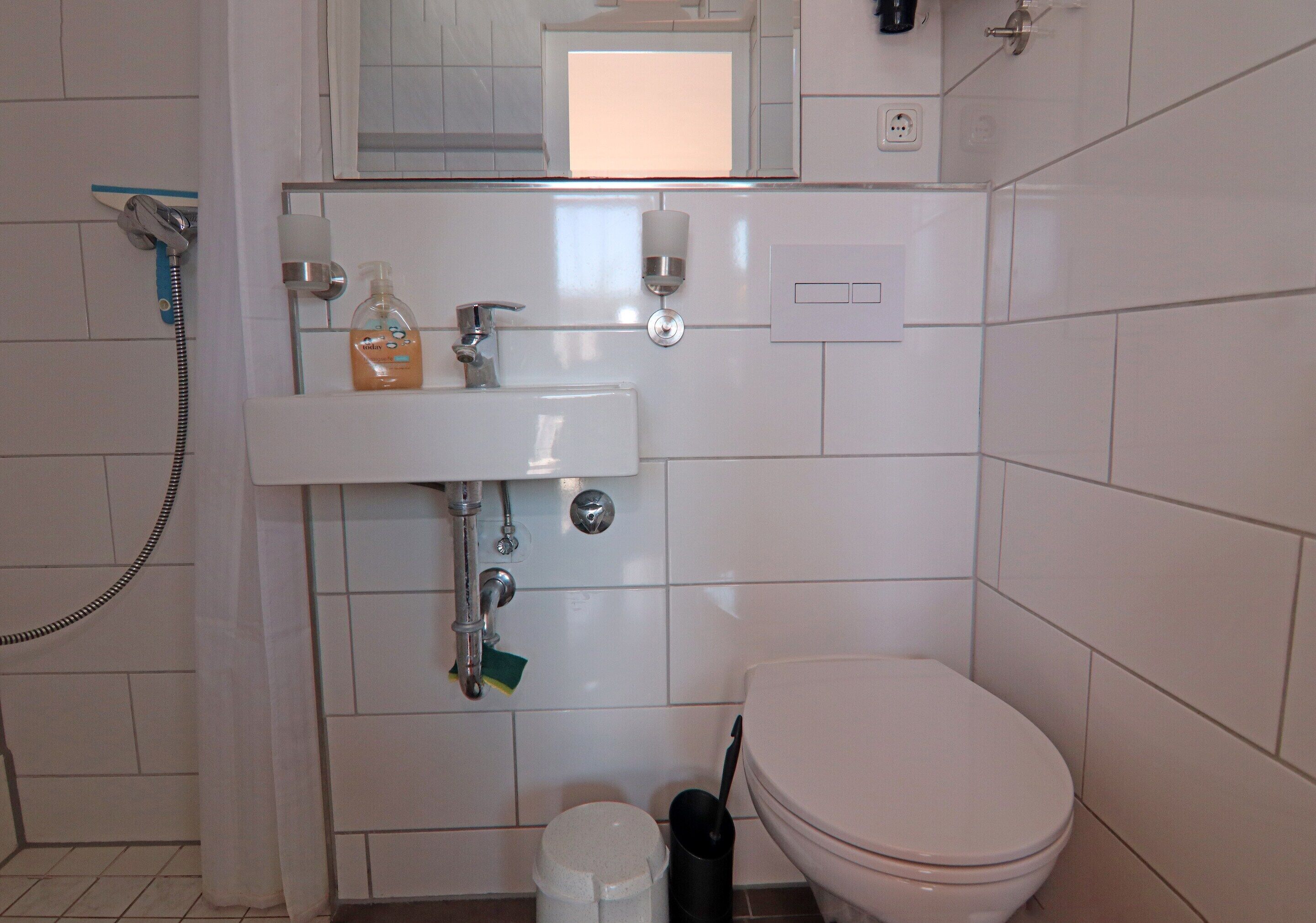 A small, clean bathroom with a toilet, sink, and shower.