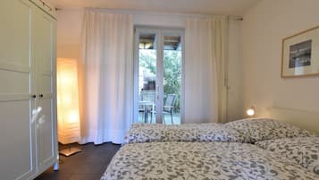 Quarto com duas camas, porta de vidro deslizante para uma varanda e um quadro pendurado na parede.