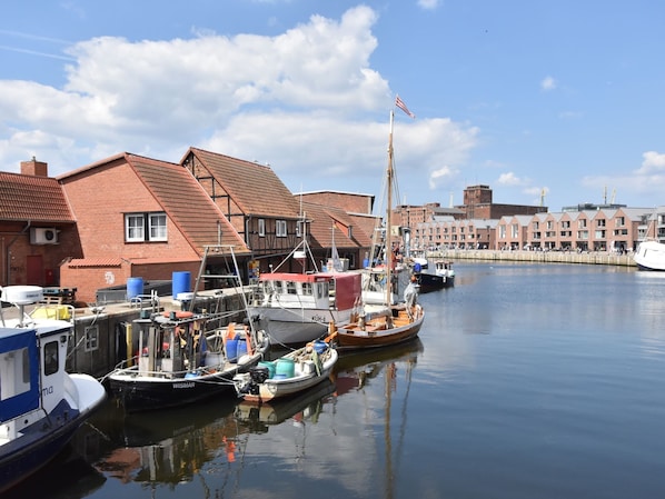 A harbor with boats docked, a flagpole with an American flag, and buildings with red roofs. - Wohnung in Wismar mit Garten (Wismar)