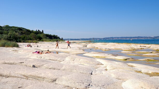 Une plage rocheuse où l’on peut voir des gens bronzer et se promener.