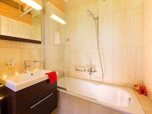 Un baño moderno con ducha de vidrio, tocador con lavamanos y bañera.