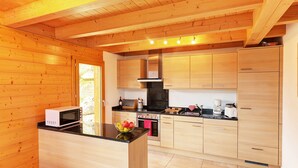 A modern kitchen with wooden cabinetry, a central island, and a stainless steel oven. - Chalet in Les Collons Near Ski Lift (Vex)