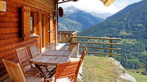 A wooden cabin with a table and chairs outside, overlooking a mountainous landscape. - Chalet in Les Collons Near Ski Lift (Vex)