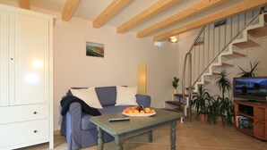 A living room with a sofa, a table with fruit, a TV, and a staircase. - Modern Holiday Home in Steffenshagen With Terrace (Steffenshagen)