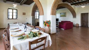 A dining area with a long table set for a meal, surrounded by brick arches and wooden beams. - Belvilla by OYO Villa Santa Caterina (Cortona)