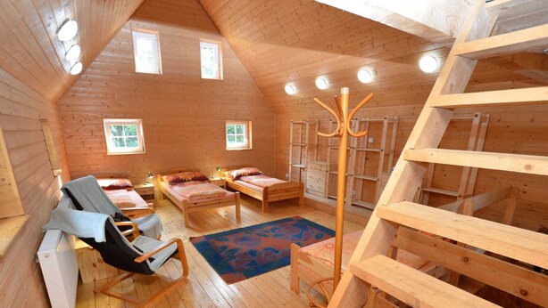 A cozy cabin with two wooden beds, a chair, a heater, and a wooden staircase. - Bedroom Farmhouse by the Woods (Malecov)