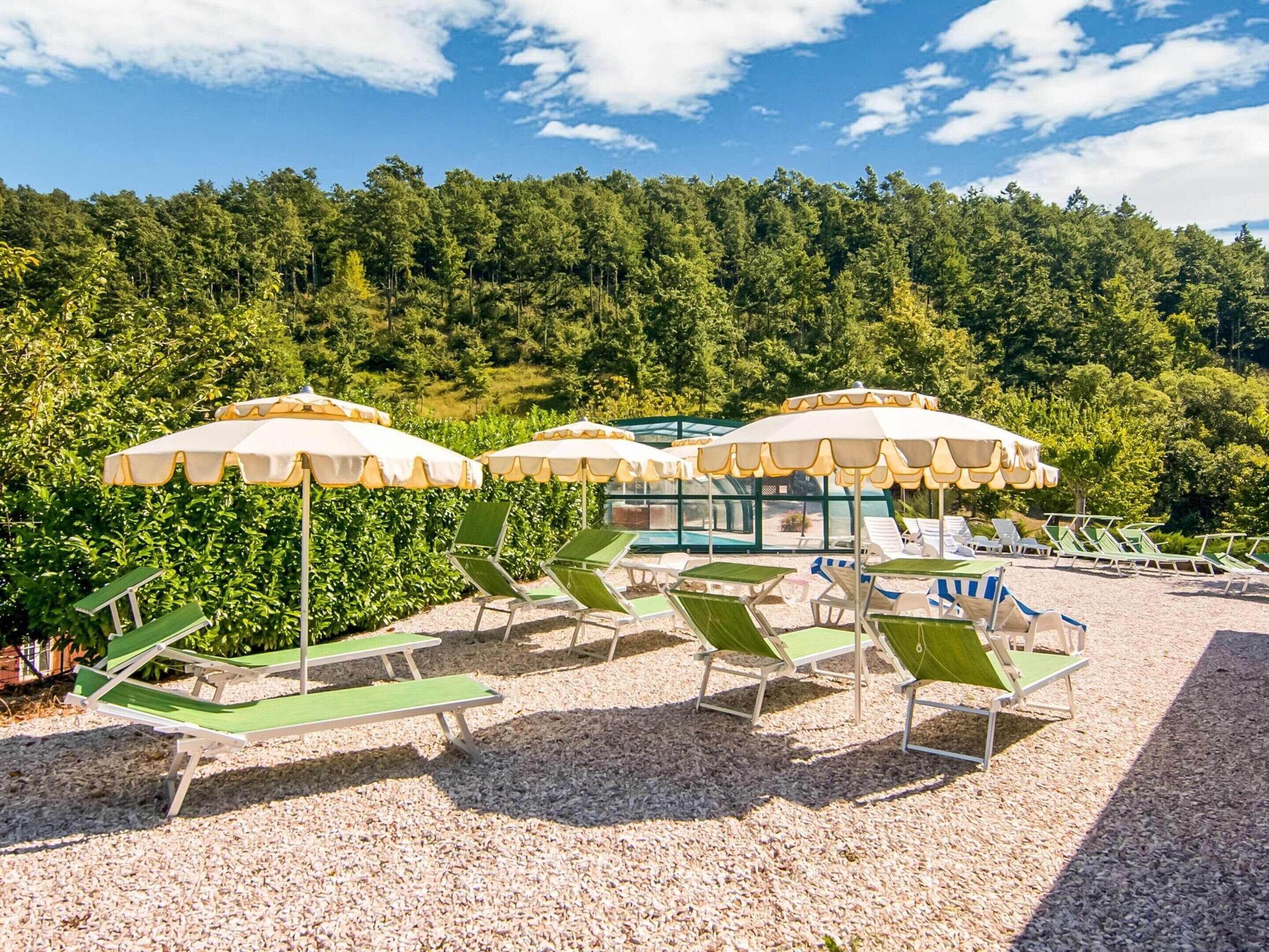 A beach area with green lounge chairs and white umbrellas.