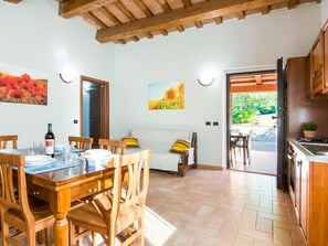 A dining area with a wooden table and chairs, a sofa, and a painting of sunflowers. - Farmhouse in Apecchio With Pool (Apecchio)