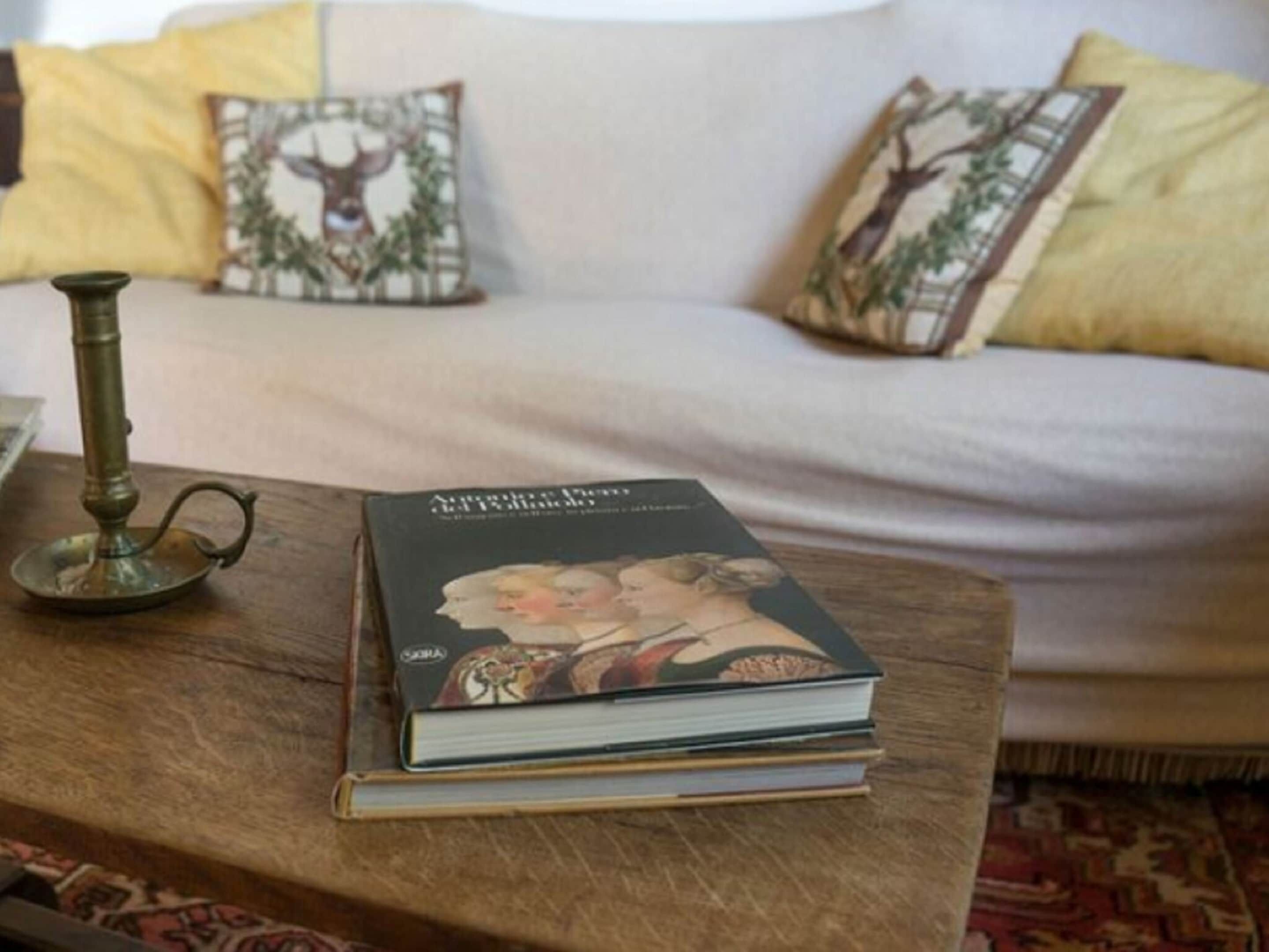 Un libro titulado 'El retrato de Dorian Gray' sobre una mesa de madera en una sala de estar con un sofá blanco y cojines decorativos.