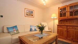 Ein gemütliches Wohnzimmer mit einer Couch, einem Couchtisch mit Blumen und einer Stehlampe sowie einem Schrank.
