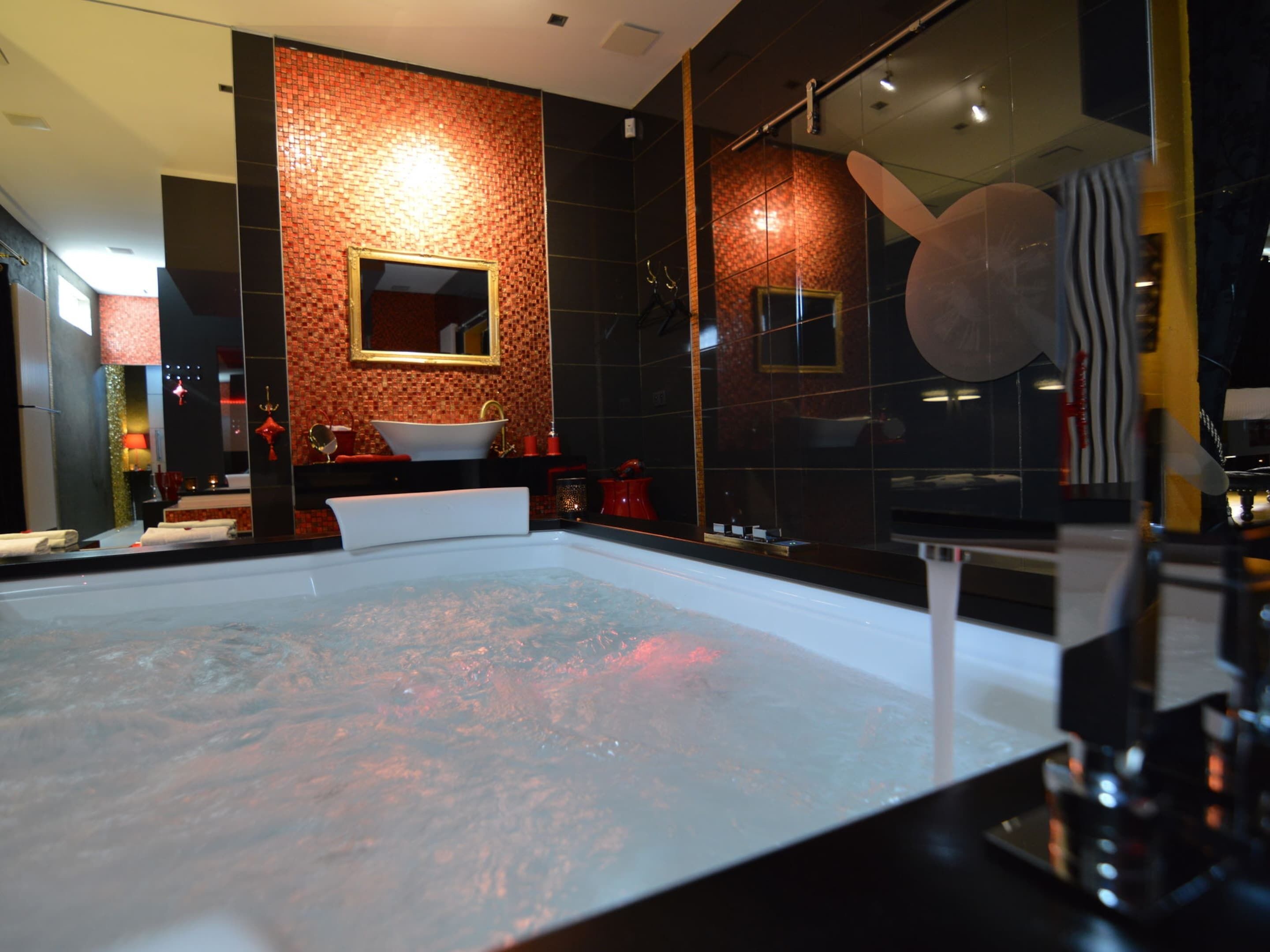 Ein modernes Badezimmer mit einer großen Badewanne, einem Spiegel und einem Waschbecken.