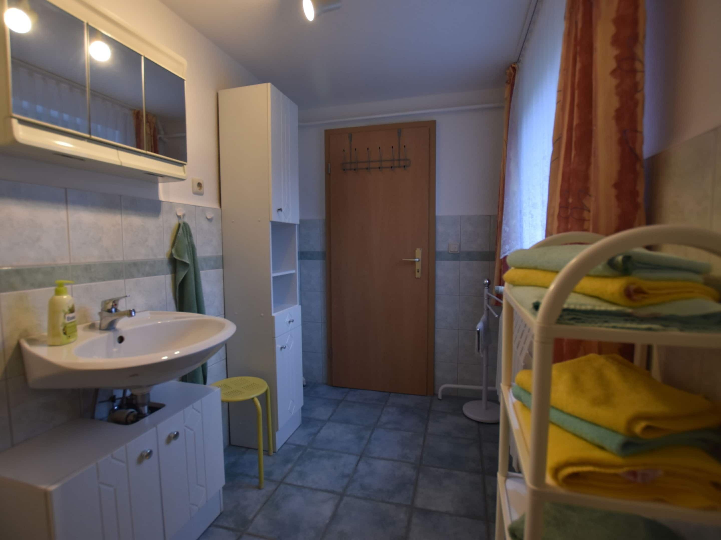 Un baño pequeño con lavamanos, espejo, armarios y una puerta que da a la zona de ducha.