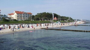 Ein Strand mit klarem Wasser, einem Leuchtturm und einem Gebäude mit rotem Dach.