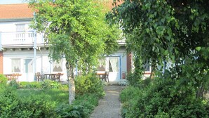 Ein Gartenweg, der zu einem Gebäude mit Außenbestuhlung führt.