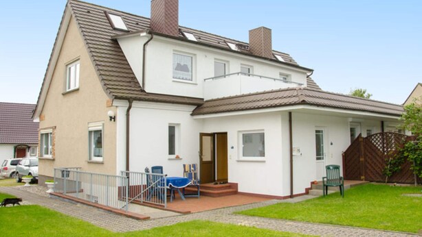 A two-story house with a sloped roof, a front porch, and a small garden area. - Stilvolle Wohnung mit Garten in Rerik (Rerik)