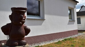 Un edificio con fachada blanca y base roja, una ventana y una estatua de piedra.