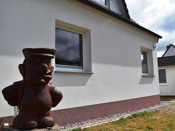 Um edifício com fachada branca e base vermelha, uma janela e uma estátua de pedra.
