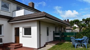 Una casa de dos pisos con puerta principal, un pequeño porche y un camino de ladrillo que lleva a la entrada.