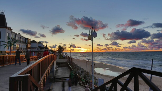 A wooden boardwalk leading to a beach with a sunset in the background. - Cozy Holiday Home in Mielno near Lake (Mielno)