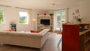 A modern living room with a sofa, TV, and a red accent wall. - Countryside Holiday Home in Stoumont With Terrace, Garden (Stoumont)