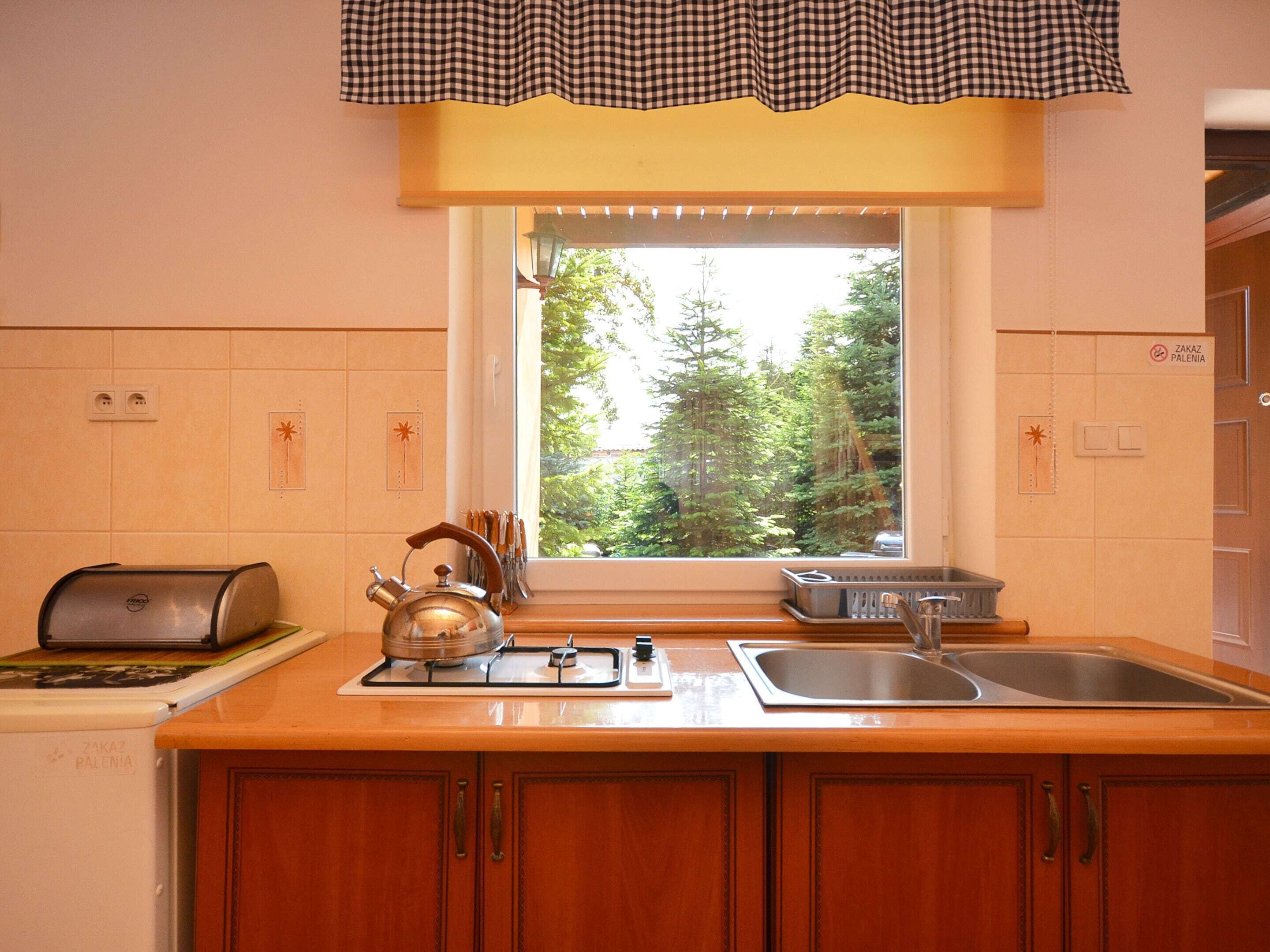 A kitchen with a window, a kettle, a toaster, and a sink.