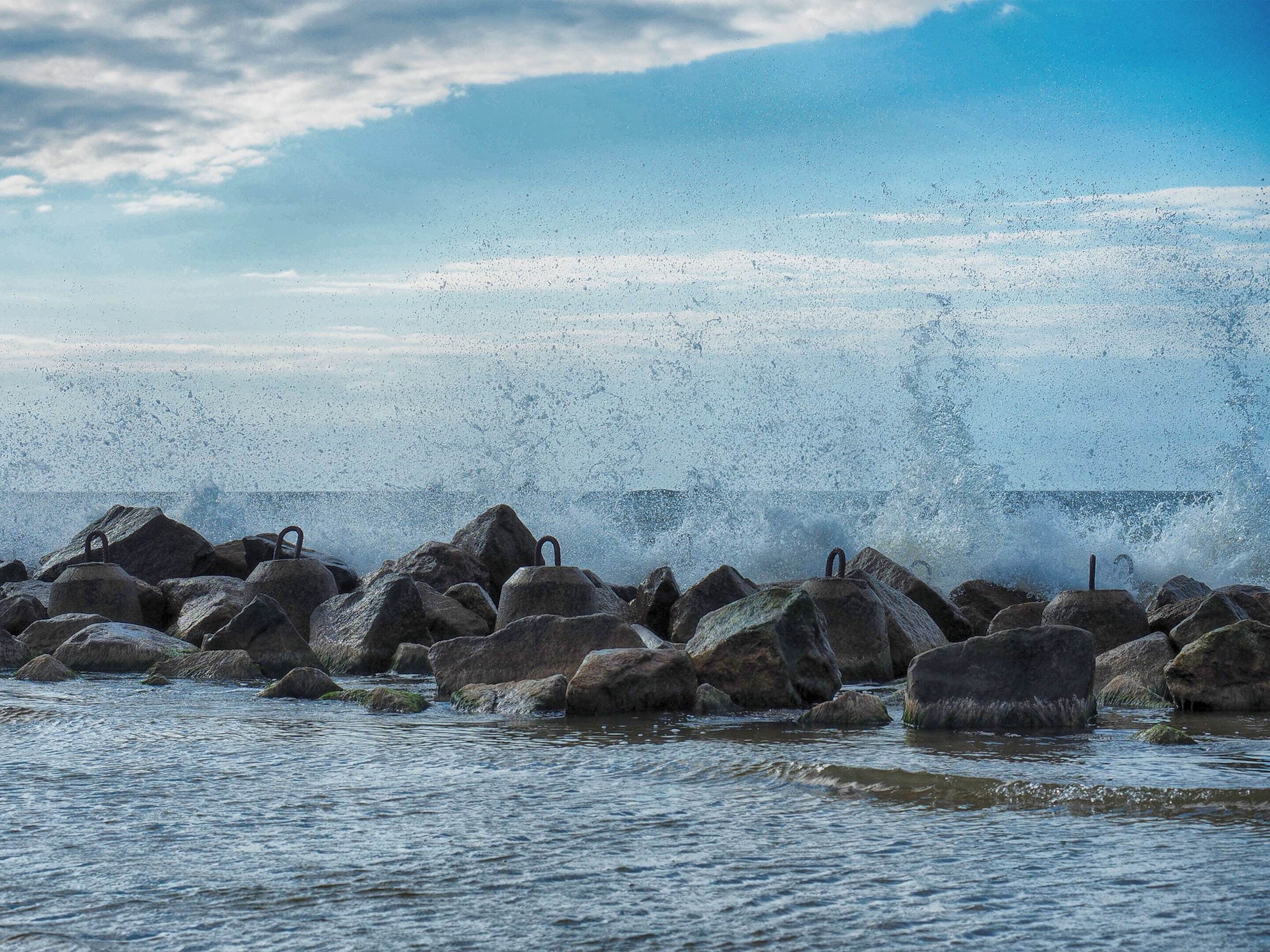 A rocky shoreline with waves crashing against large boulders.