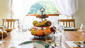 Une table à manger dressée avec des assiettes, des verres et une présentation de fruits.