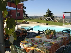 An outdoor dining area with a pool, surrounded by a stone wall and a view of hills. - Villa With Private Swimming Pool (Tredozio)