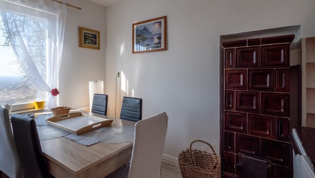 A dining area with a table, chairs, a laptop, a basket, and a window with sheer curtains. - Holiday Home in Prilipje With Terrace (Jastrebarsko)