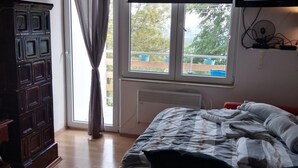A bedroom with a bed, a television mounted on the wall, a window with curtains, and a wooden cabinet. - Holiday Home in Prilipje With Terrace (Jastrebarsko)
