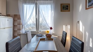 A dining area with a table, chairs, a basket, a lamp, and a window with sheer curtains. - Holiday Home in Prilipje With Terrace (Jastrebarsko)